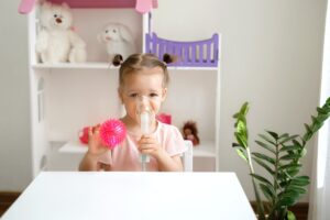 Kid in an inhalation mask from a nebulizer breathes steam